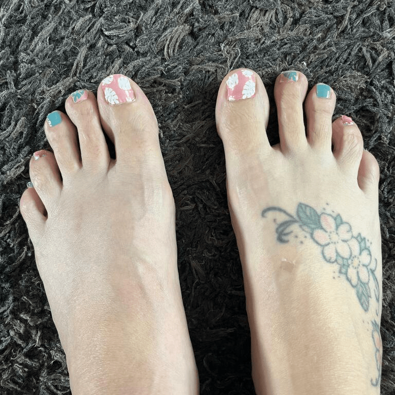 Feet wearing tropical flamingo and monstera leaf pedicure nail wraps in pink coral and teal