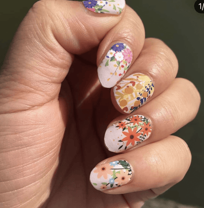 Delicate floral nail wraps on hand featuring colourful flower patterns for at-home manicure