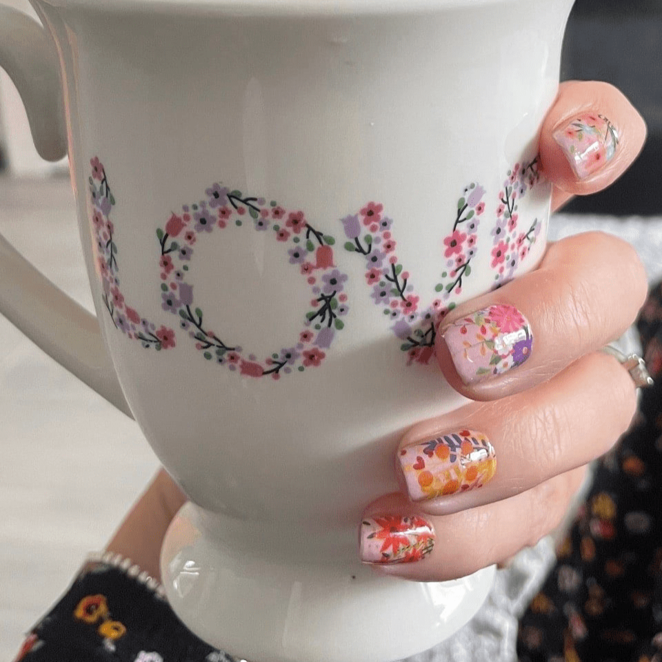 Hand holding love mug wearing pink floral nail wraps with watercolour flower art
