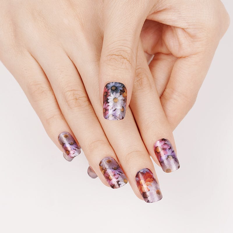 Hands wearing colourful floral nail wraps with watercolour daisy patterns for spring manicure