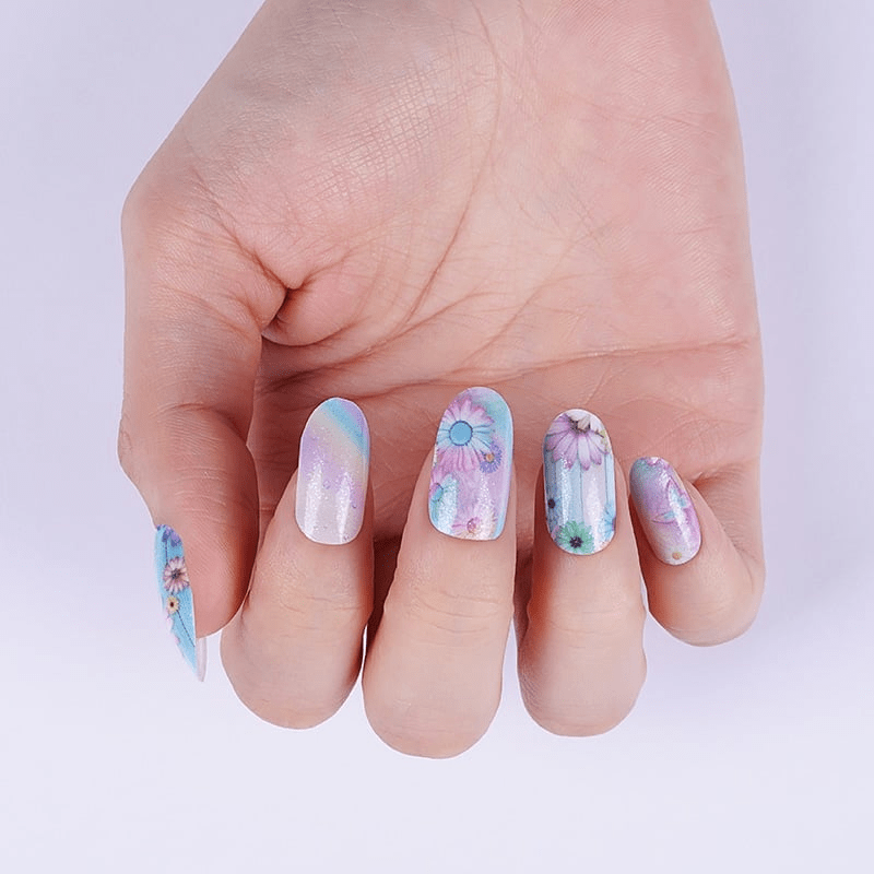 Close-up of pastel gel nail wraps with delicate watercolour flower patterns in blue and purple