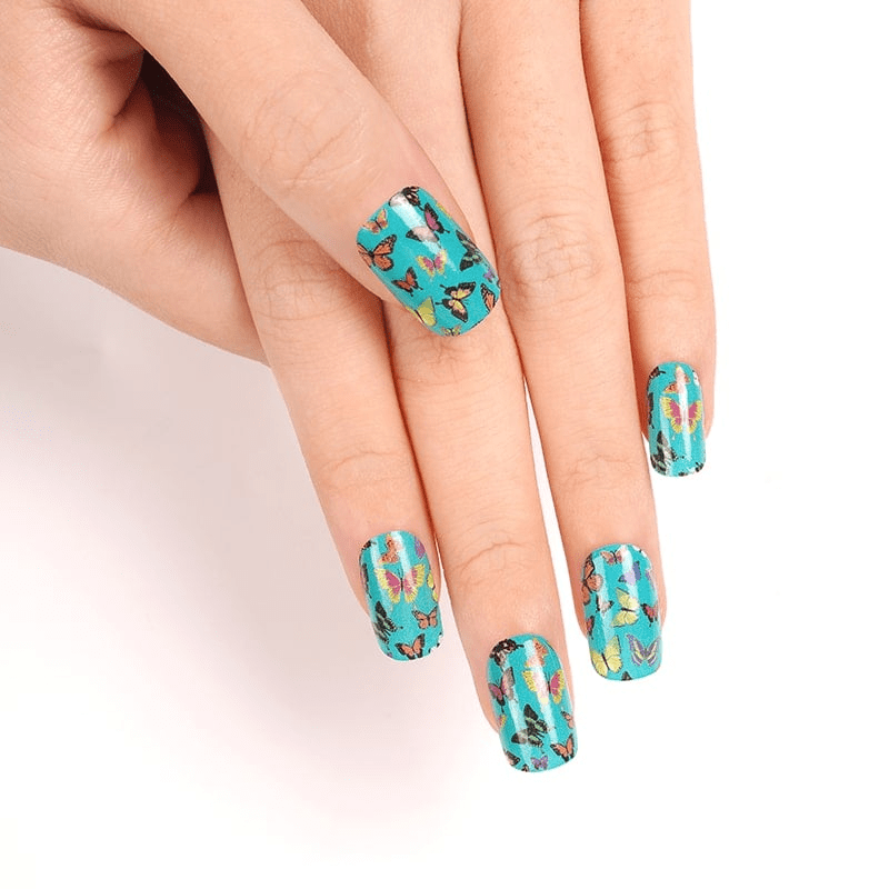 Hand wearing turquoise butterfly nail wraps with orange and green design