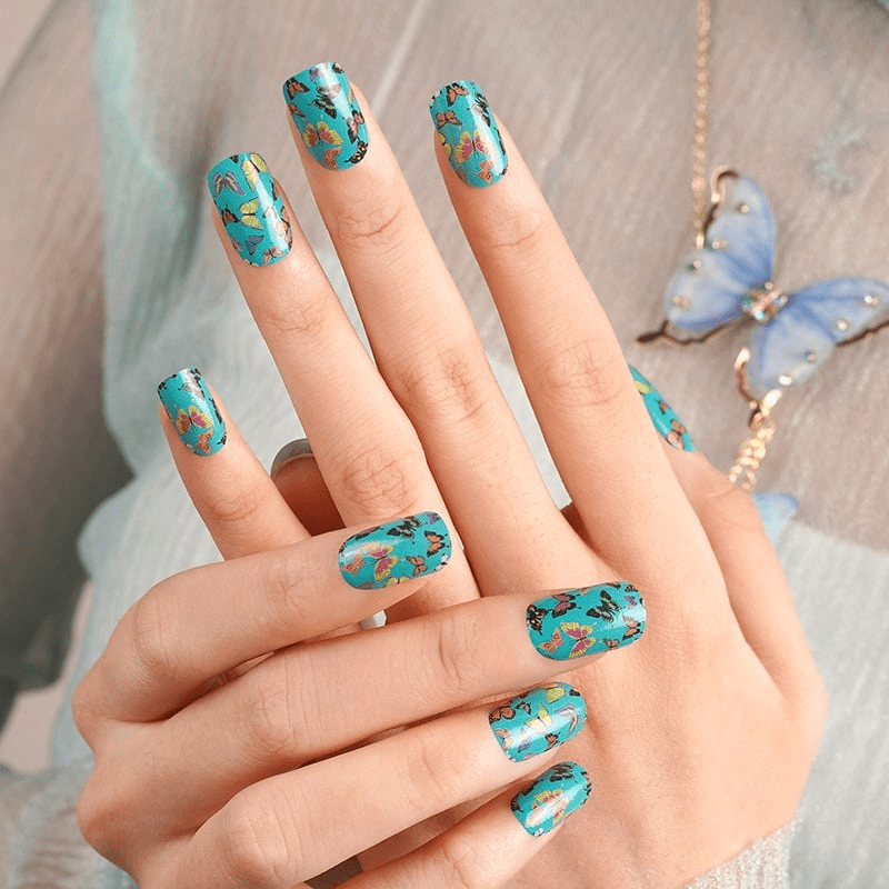 Turquoise nail wraps with colourful butterfly pattern on hand manicure