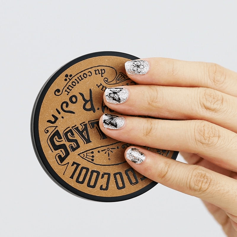 Silver metallic butterfly gel nail wraps displayed on hand over circular wooden surface