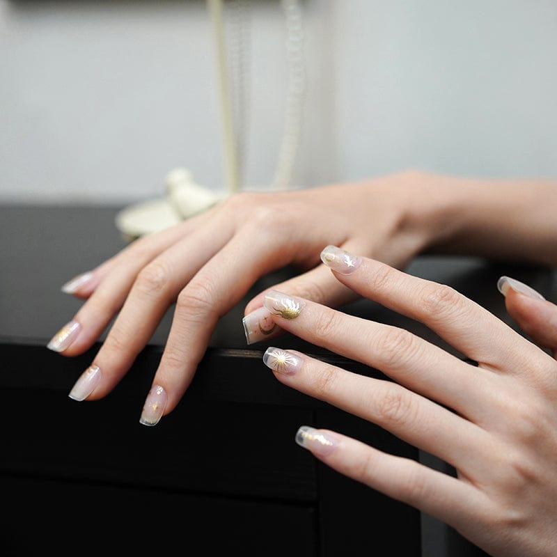 Hands showing nude manicure with gold star nail art celestial designs