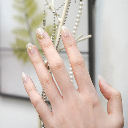 Hand displaying nude nail art with delicate gold celestial star patterns