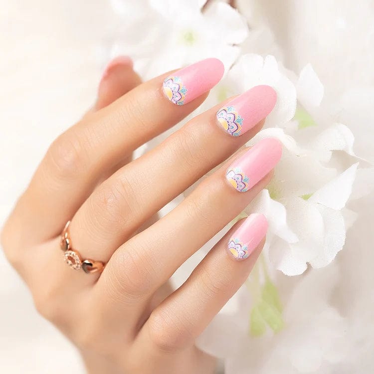 Pink gradient nail wraps with white daisy floral design on hand holding flowers