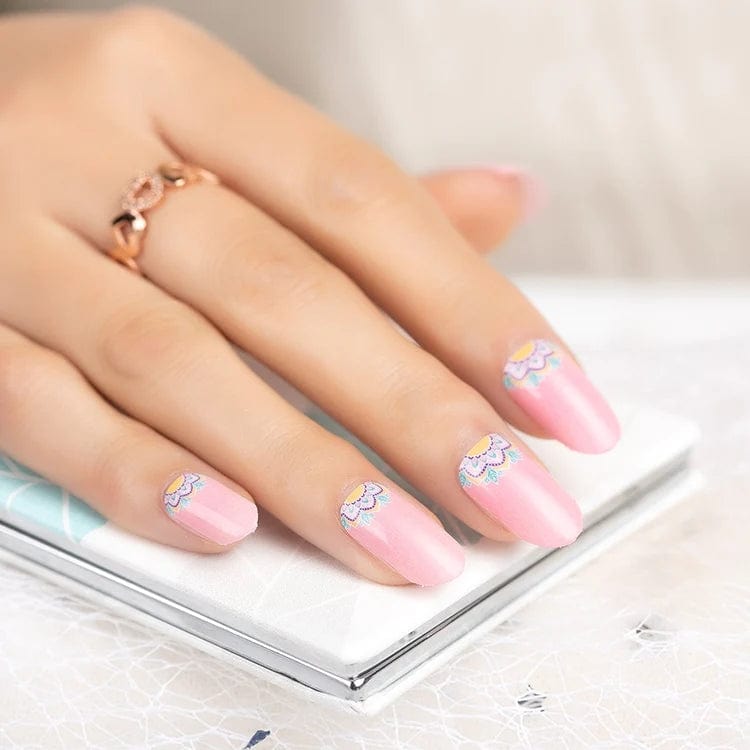 Pink nail wraps with white daisy pattern on hand holding ring