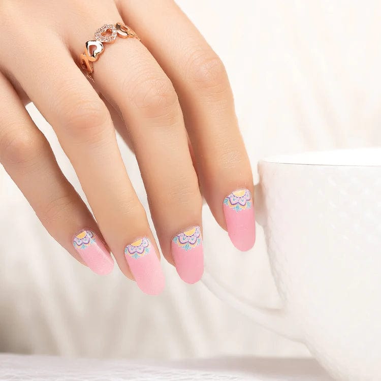 Hand displaying pink gel nail wraps featuring delicate white daisy nail art