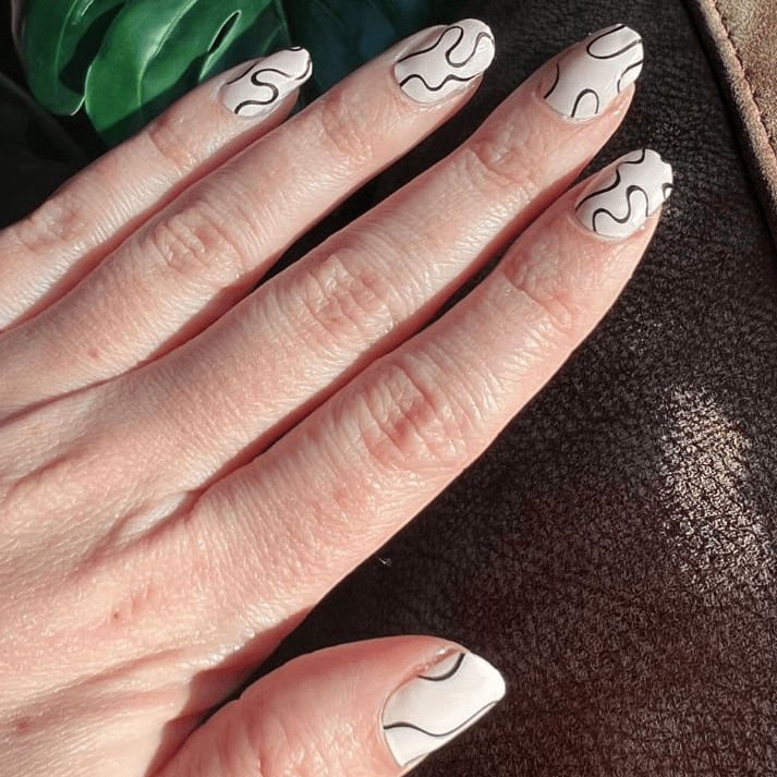 Hand displaying black squiggly line nail art wraps in minimalist contemporary design