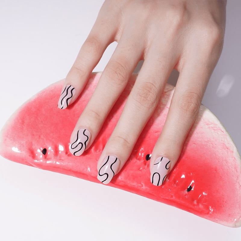 Abstract wavy nail wraps on hand holding pink watermelon slice showing monochrome nail art