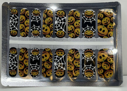 Halloween nail wraps sheet featuring orange pumpkin faces and white spider web designs
