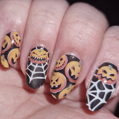Halloween gel nail wraps with pumpkin and spider web patterns on fingernails