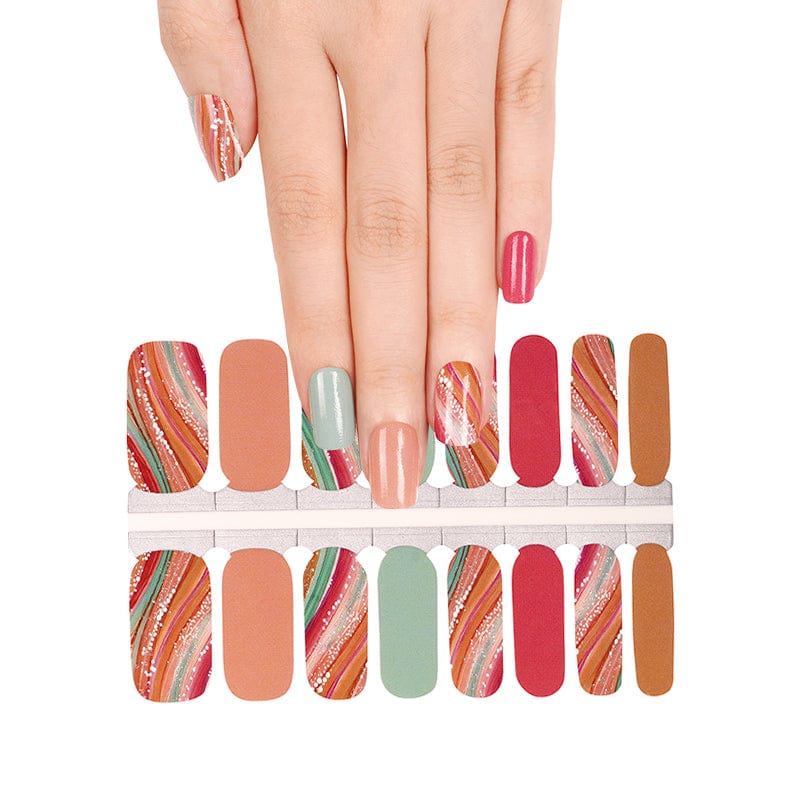 Hand wearing autumn-themed nail wraps with coral, sage green, and swirl patterns for at-home manicures