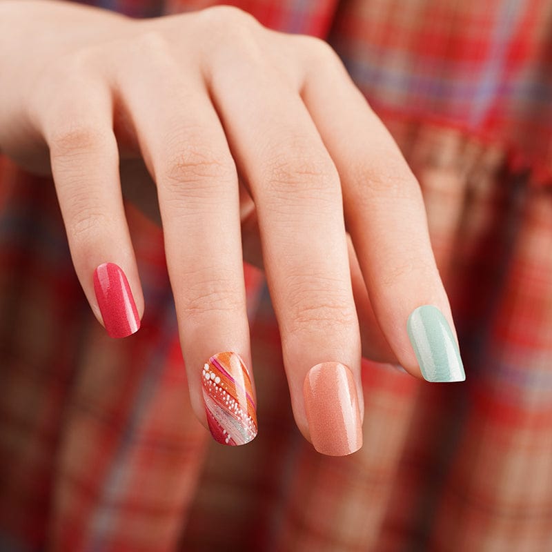 Colourful nail wraps on hand with coral, mint green and glittery accent nail designs
