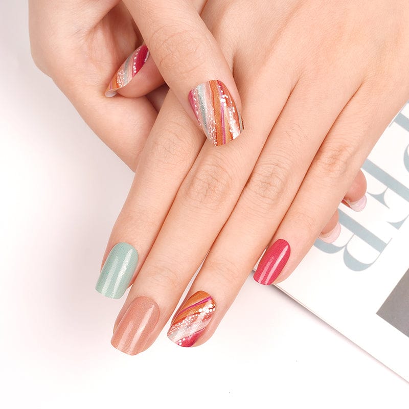 Mixed design nail wraps on hands with coral, sage green and glittery accent nails