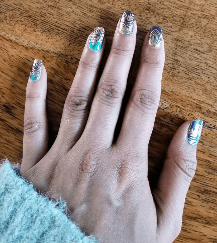 Hand wearing navy blue non-UV nail wraps with golden lotus botanical patterns and metallic gradient finish