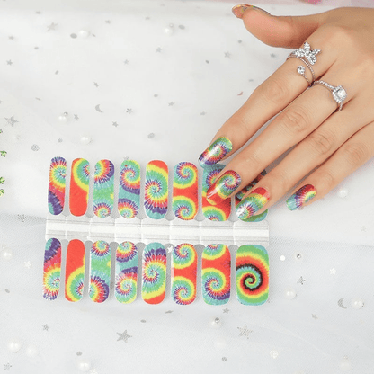 Tie-dye nail wrap sheet with rainbow spiral patterns alongside matching manicured nails