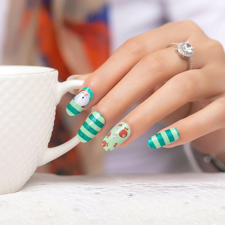 Hand wearing festive Christmas nail wraps with Santa and striped green patterns
