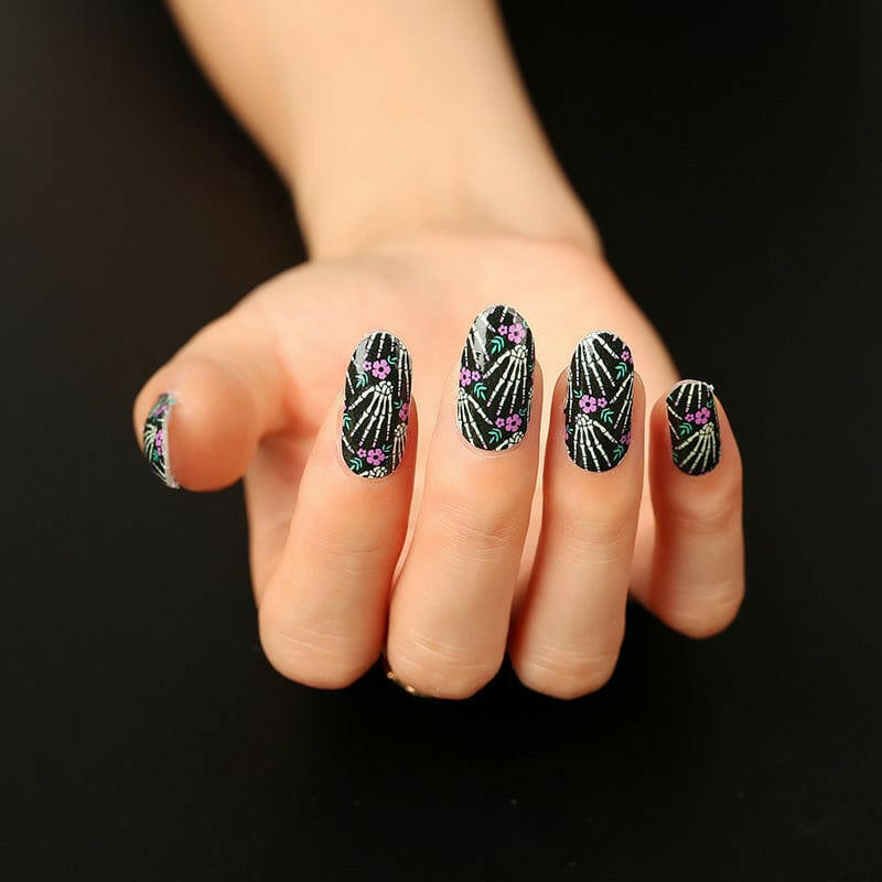 Gothic nail art wraps featuring skeleton bones pattern on black background displayed on hand