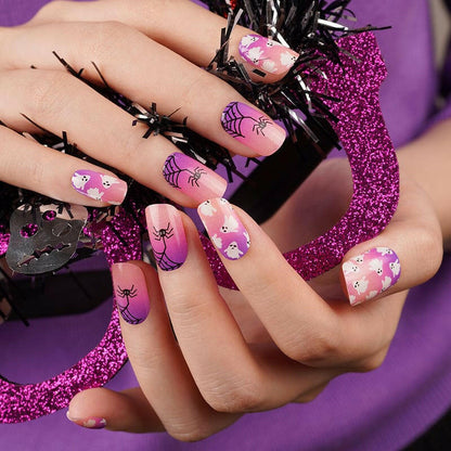 Spooky Halloween nail wraps in pink and purple with skulls and spider web patterns on hand