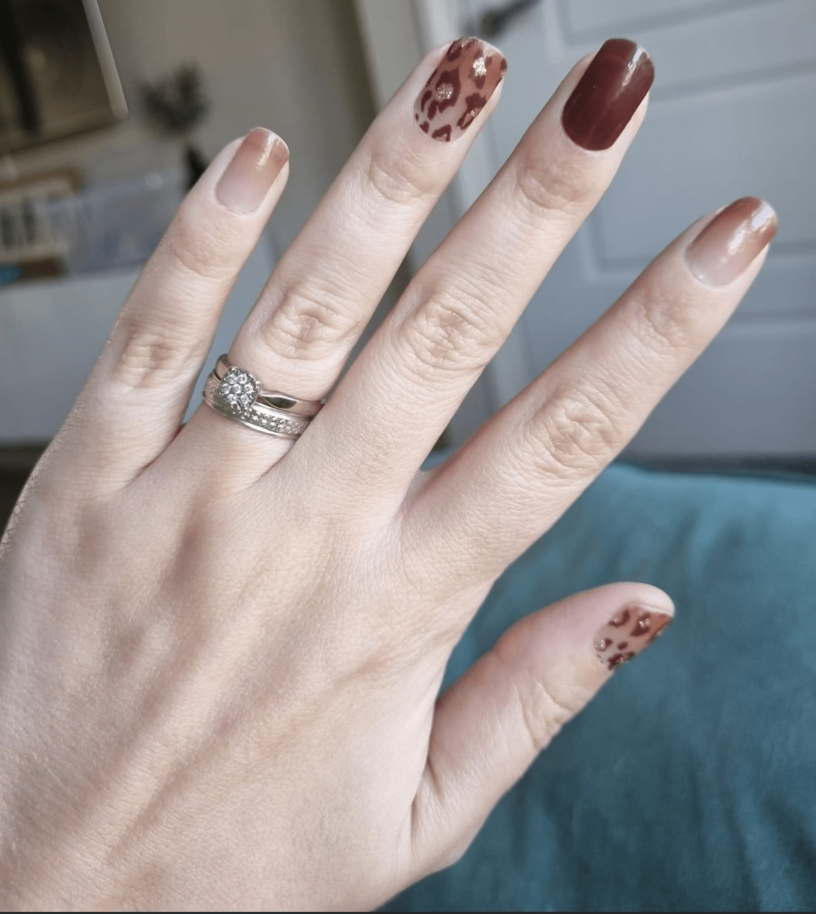 Hand displaying brown leopard print nail wraps with nude and dark chocolate shades