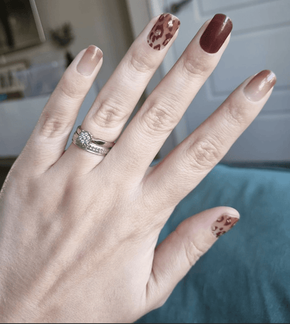 Hand displaying brown leopard print nail wraps with nude and dark chocolate shades