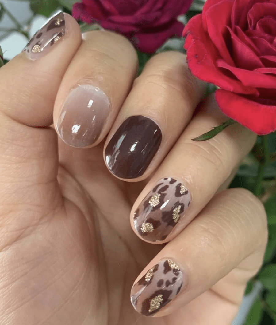 Hand showing brown and nude nail wraps with leopard print design and glossy finish