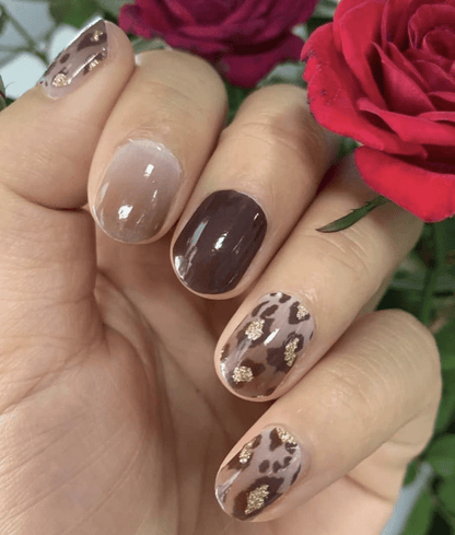 Hand showing brown and nude nail wraps with leopard print design and glossy finish