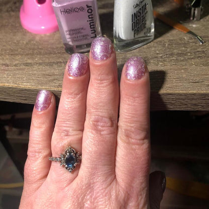 Pink glitter gel nails on hand showing sparkly manicure with nail accessories