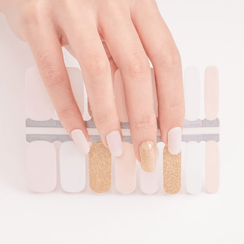 Hand demonstrating nail wrap application with pink nude and gold glitter gel nail wraps