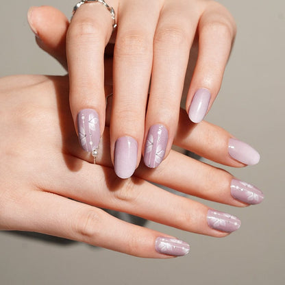 Hands displaying pink matte nail wraps with white cherry blossom floral patterns