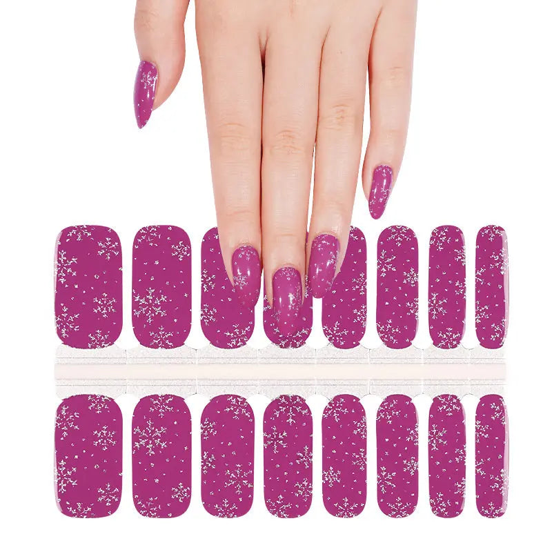 Purple glitter nail wraps with white snowflake pattern shown on hand with product sheet