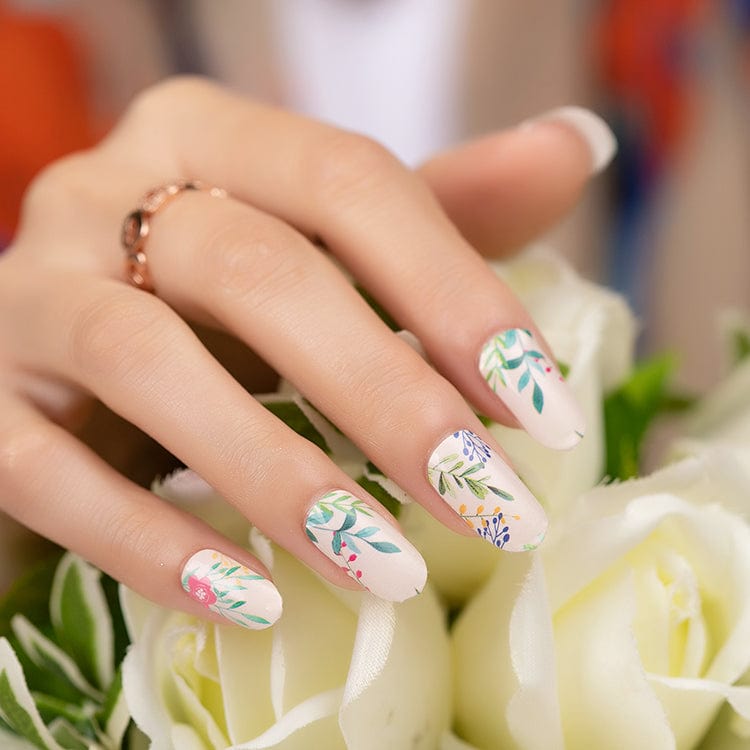 Hand wearing botanical nail wraps with pink flowers and sage green leaves on cream base