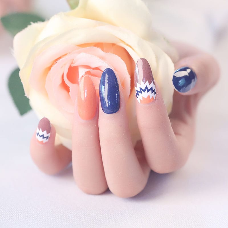 Navy blue orange nail art wraps with white chevron accent design on hand