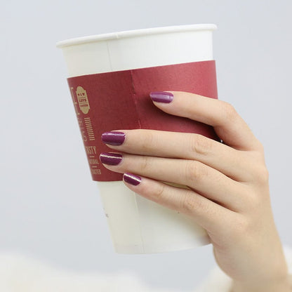 Hand holding coffee cup showing burgundy glossy nail wraps at-home manicure