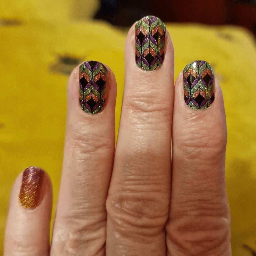 Hand showing bronze metallic gradient nail wraps with autumn leaf design