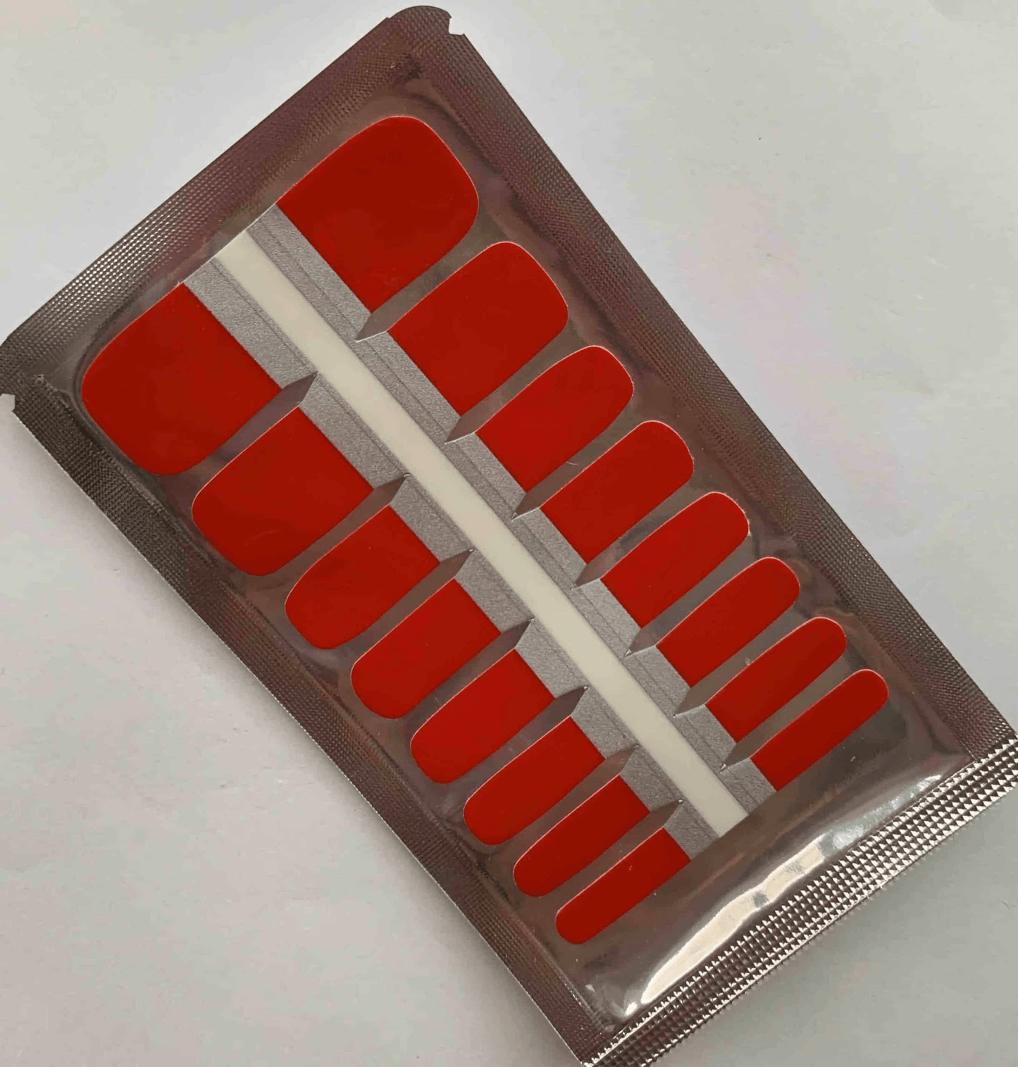 Cherry red glossy pedicure nail wraps in clear packaging showing complete set