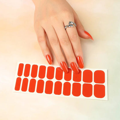 Hand with bright red glossy nail wraps next to sheet of cherry red wide fit nail wraps