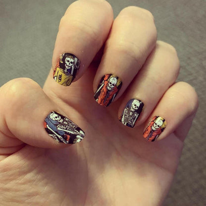 Hand wearing spooky skeleton nail wraps with colourful gothic Halloween nail art design