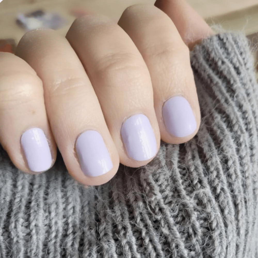 Lavender purple nail wraps on hand against grey knitted jumper for elegant manicure