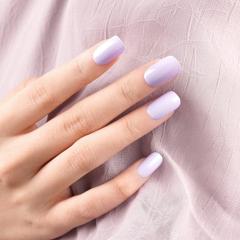 Matte lavender nail wraps on hand against soft purple fabric background