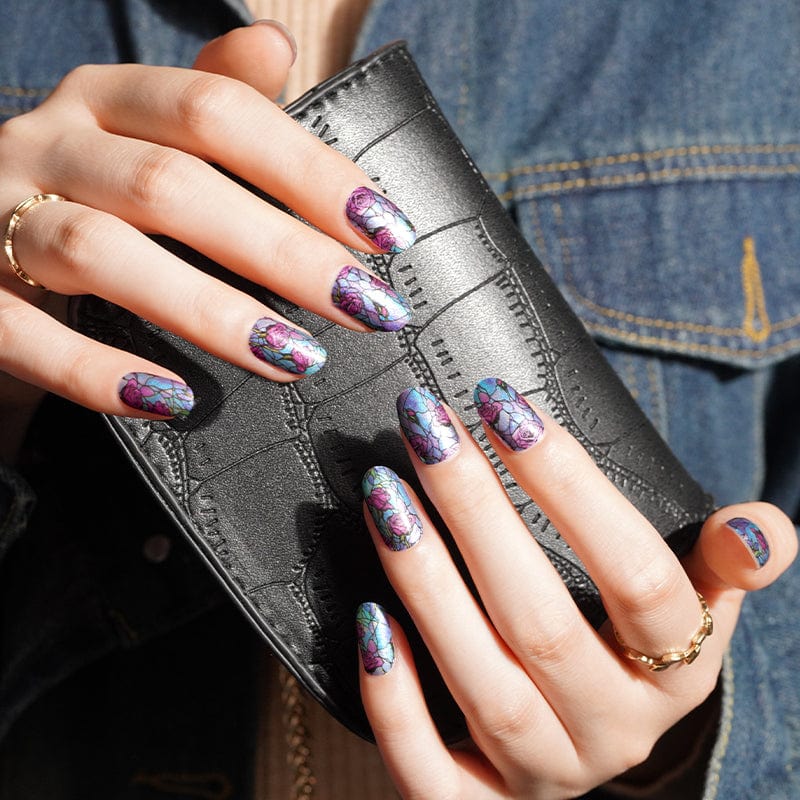 Hands holding wallet showing stained glass floral nail wraps in purple pink botanical design