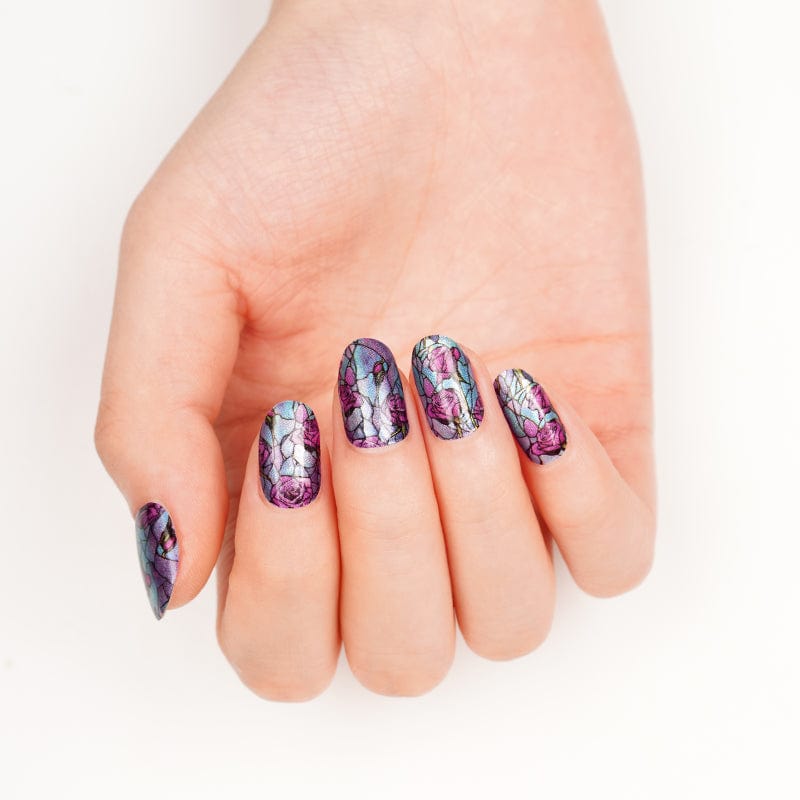 Purple and pink floral nail wraps on hand displaying stained glass rose pattern manicure