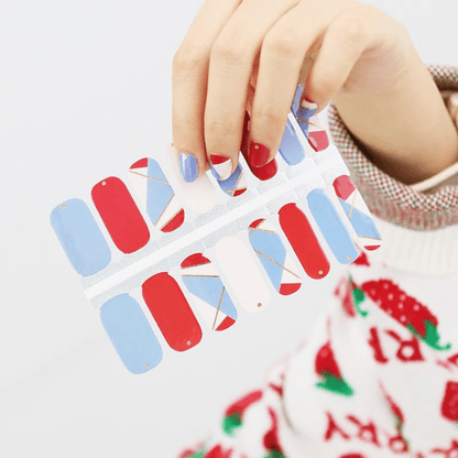 Hand holding red blue geometric nail wraps with architectural colour block patterns