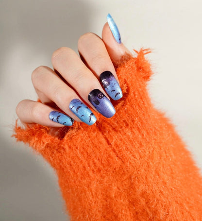Blue gradient gel nail wraps with black bat silhouettes on hand for Halloween manicure