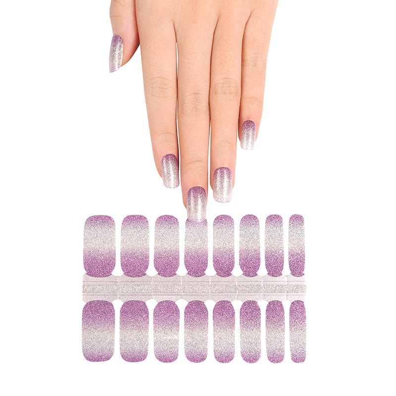 Hand reaching for lilac to silver ombre nail wrap strips for at-home manicure
