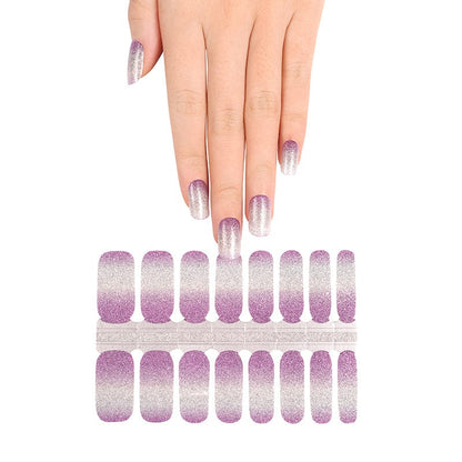 Hand reaching for lilac to silver ombre nail wrap strips for at-home manicure