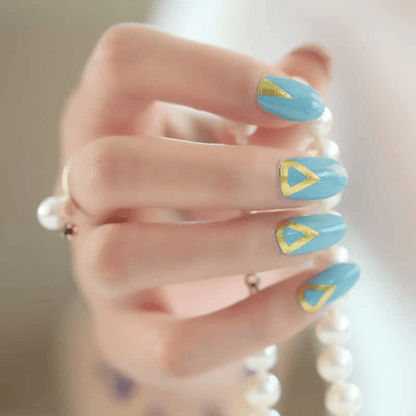 Hand wearing turquoise nail wraps with gold geometric patterns holding pearl necklace