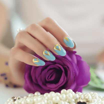 Teal nail wraps with gold triangle design on hand holding purple rose